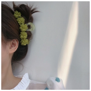 Détail d'une pince à cheveux muguet vert forêt sur une coiffure élégante de côté