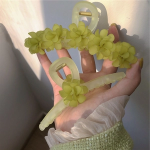 Détail de pinces à cheveux muguet vert forêt avec accents floraux 3D sous lumière naturelle