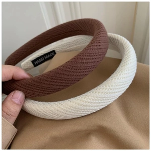 Close-up of thick knitted padded headbands in brown and beige with hand made label