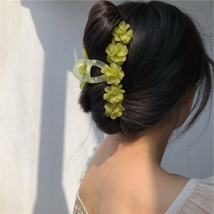 Vue détaillée de la pince à cheveux muguet fixant un chignon sous la lumière du soleil