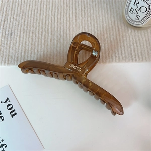 Vue détaillée d'une pince à cheveux ambre avec inscription sur fond en tissu beige
