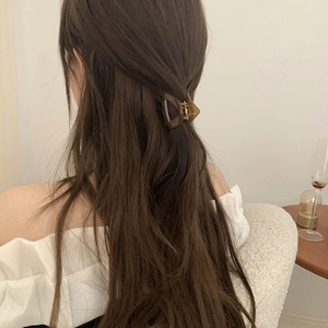 Detail view of a small brown geometric hair claw clip securing a chic half-up hairstyle