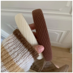 Detail of two knitted sponge headbands in cream and brown showing thick ribbed texture