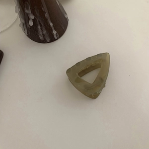 Detail view of small amber triangle hair claw clip with dark green marble texture