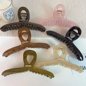 Grandes pinces à cheveux en acrylique en cinq couleurs sur une surface en maille blanche