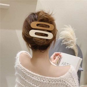 Detail of matte hair clips in cream and coffee colors on woman's wavy hair