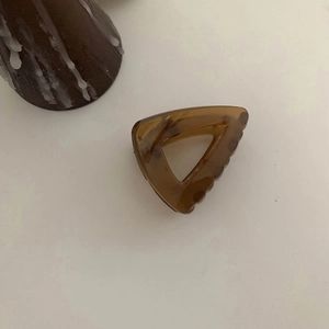 Detail view of triangular coffee brown hair claw clip with a glossy translucent finish