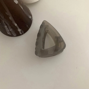Macro detail of a minimalist translucent brown triangle hair claw clip on white surface