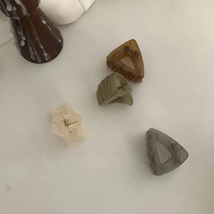 Detailed set of four mini translucent hair clips in amber, green, and gray finishes