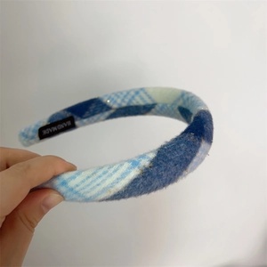 Detailed close-up of blue and white plaid fabric headband with a handmade textile label