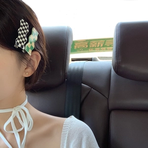 Detail of two checkered hair clips worn on the side, black-white and green-white wave patterns