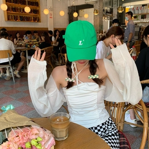 Close-up of a green baseball cap and simple hair clip styled in a modern cafe setting