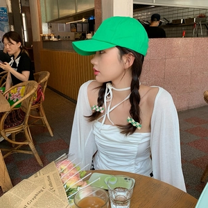 Close-up of a stylish bright green canvas baseball cap worn in a cozy cafe setting