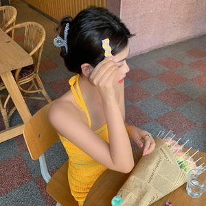 Close-up of checkerboard hair clips on hair in an outdoor cafe setting with soft lighting