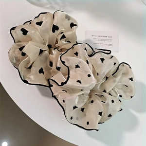 Détail d'un chouchou géant en organza blanc cassé avec motifs cœurs et pois noirs