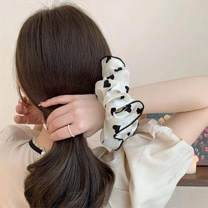 Gros chouchou en soie crème avec motifs cœurs noirs sur un chignon élégant de femme