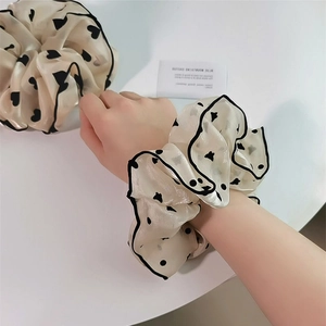 Détail du chouchou géant crème avec motifs de cœurs noirs et pois sur tissu satiné