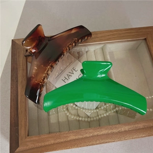 Dettaglio di grandi mollette per capelli tartarugate e verde brillante su vassoio