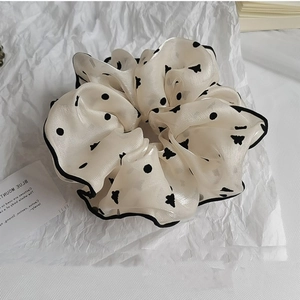 Détail d'un grand chouchou en organza blanc cassé avec pois noirs et motifs de papillons