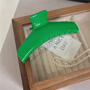 Dettaglio di un grande fermaglio per capelli verde su vassoio con perle e carta