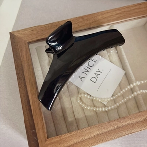 Dettaglio di una grande clip per capelli nera lucida dal design minimalista elegante