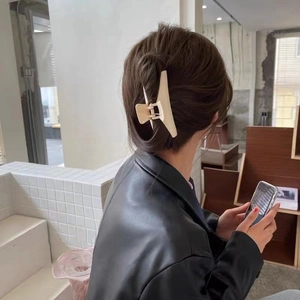 Dettaglio di una grande molletta per capelli beige opaco su capelli castano scuro