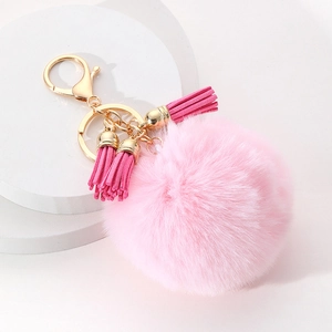 Détail d'un porte-clés pompon en fausse fourrure rose avec trois glands assortis en daim