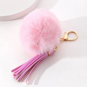 Pink plush ball keychain with purple tassel and gold metal hook on white background