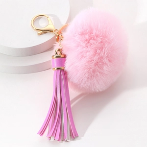 Close-up of pink faux fur pompom keychain with leather tassel and gold metal hardware