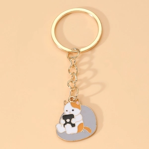 Gros plan d'un adorable porte-clés chat en émail avec anneau doré sur fond rose