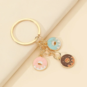 Detail of three colorful donut pendants in pink, blue and chocolate with gold keyring