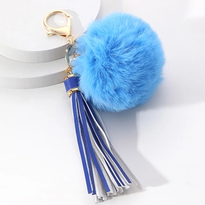 Close-up of fluffy sky blue pom pom and blue-white leather tassel with golden clasp