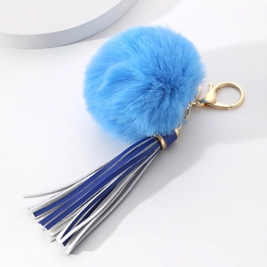 Detailed shot of bright blue plush pompom keychain with navy blue and white tassels