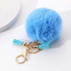 Détail du porte-clés pompon bleu ciel avec fermoir doré et pampilles en daim doux