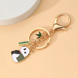 Détail d'un porte-clés panda doré avec charmes en bambou et fermoir mousqueton