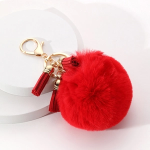 Détail d'un porte-clés pompon en fourrure rouge avec fermoir doré et pampilles à franges