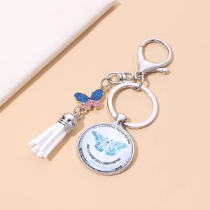 Detail of butterfly keychain with silver alloy clasp, white tassel, and memorial glass pendant