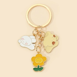 Close-up of golden keychain with cute white puppy and yellow dog charms on beige background