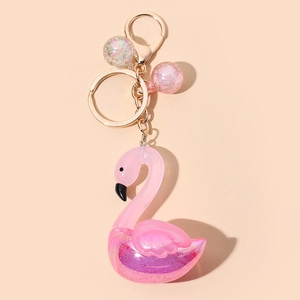 Porte-clés flamant rose avec paillettes violettes et fermoir doré sur fond de ton chair