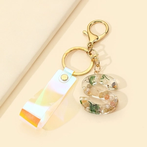 Detail of resin letter S keychain with dried flowers, moss, and iridescent PVC strap