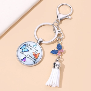 Macro detail of butterfly glass pendant keychain with inspiring quote and white tassel