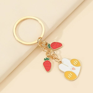 Detail of cute bunny and strawberry charms on a golden metal keychain pendant