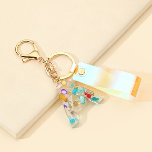 Close-up of resin letter A keychain with colorful glitter stones and holographic strap