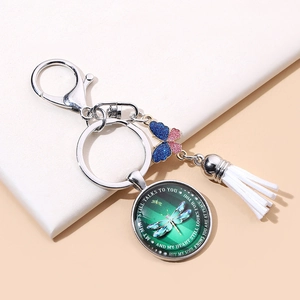 Detail view of dragonfly keychain with blue butterfly charm and white leather tassel