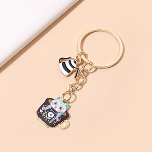 Close-up of golden keychain with cat in a teacup and coffee pot pendant detail