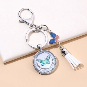 Detail of butterfly glass charm keychain with white tassel and inspirational message