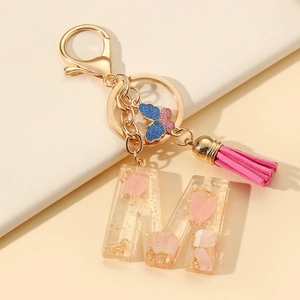Resin letter M keychain with pink flower petals, gold foil, and stylish leather tassel