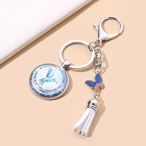 Macro detail of hummingbird memorial charm with white tassel and blue glitter butterfly