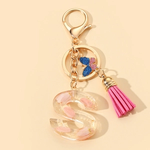 Detail of resin letter S keychain featuring pink dried petals, gold foil, and a pink tassel
