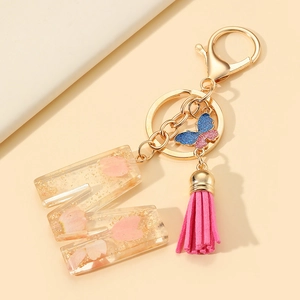 Resin letter M keychain with pink flower petals, gold flakes, and a vibrant pink tassel